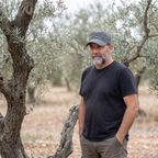 Hombre con gorra de algodón de campo gris junto a olivo