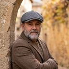 Hombre con gorra de lana de espiga gris ceniza junto a arco de piedra