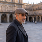 Hombre con gorra de lana clásica marrón tabaco cruzando una plaza